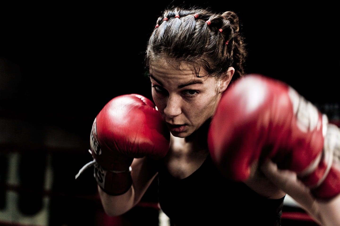 WEDSTRIJDBOKSEN VOOR VROUWEN, DAMES, MEIDEN EN MEISJES BIJ BOXING UNIVERSITY BREDA Meisje met bokshandschoenen in vechthouding tijdens bokstraining voor vrouwen bij Boxing University Breda – kracht en focus in beeld.