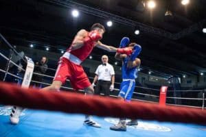 Boksactie in de ring tijdens een jeugdpartij, met een bokser in rood die aanvalt en een bokser in blauw in dekking. Op 6 april neemt Abel van Boxing University Breda deel aan het Zuid Nederlands Kampioenschap 2025.