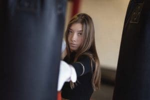 Vrouwelijke deelnemer traint geconcentreerd met bokszak tijdens een les boksen zonder sparren bij Boxing University Breda.